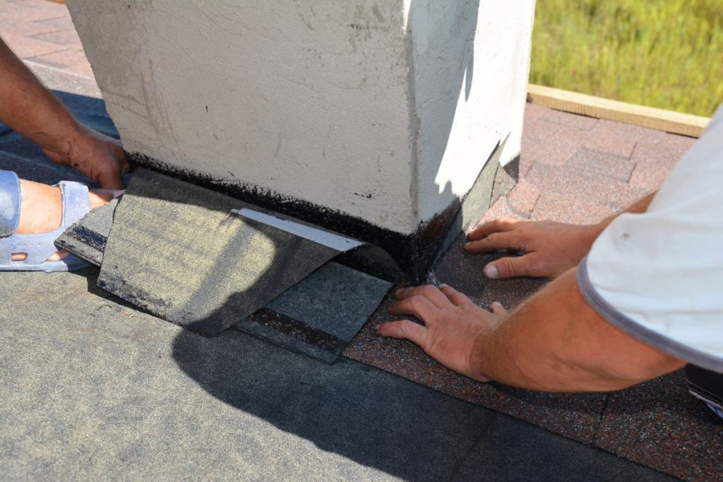 A close-up on a roofing construction, installation of asphalt shingles on roof sheathing around a house chimney, Lakeville, MN