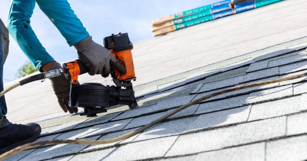 roofer installing roof shingles with nail gun in Lakeville
